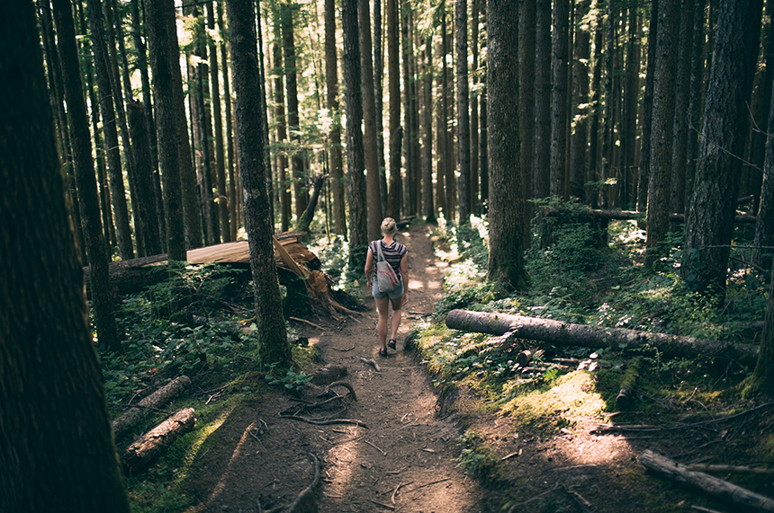 A woman walking down a wooded trail